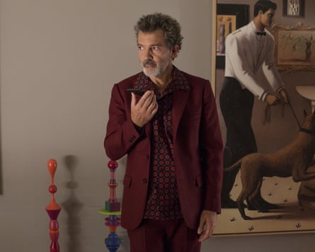 man in suit, holding a phone, and standing in front of a painting