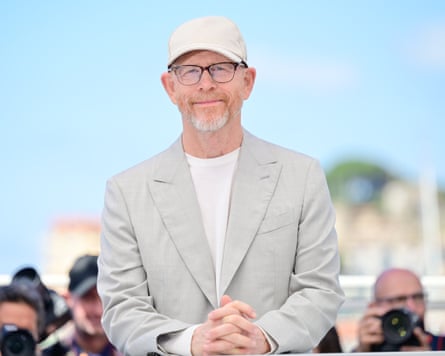 Director Ron Howard wearing a light suit and a baseball cap with his hands clasped.
