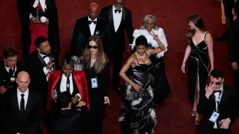 Reuters Actor and singer Teyana Taylor wearing a fitted gown of black and white feathers as she shimmies down the red carpet of the Acadamy Awards surrounded by other attendees.