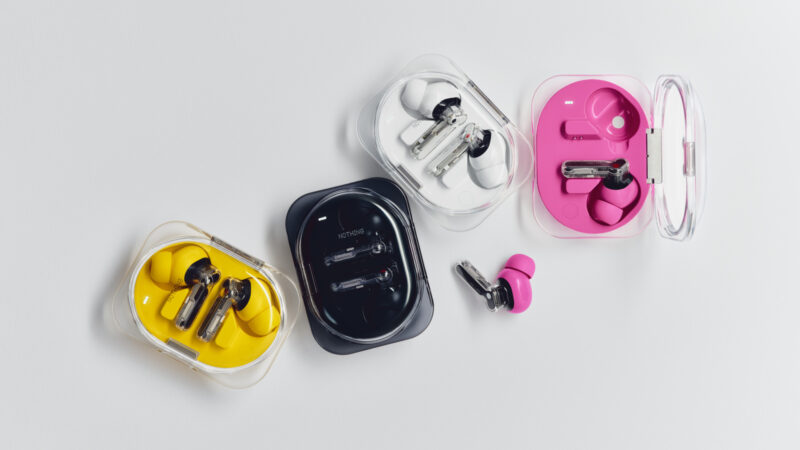 Four pairs of wireless earbuds, including the Nothing Ear (3a) in vibrant yellow, black, white, and pink—each snugly nestled in matching transparent charging cases—are artfully arranged on a pristine white surface.
