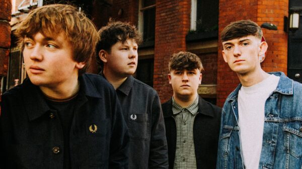 Members of 'The Cases' stand in front of a red brick building.