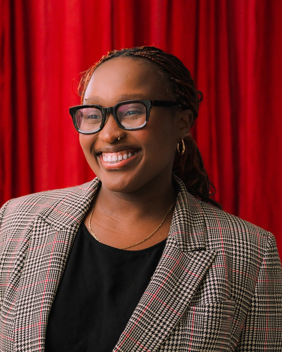 Sandulela Asanda smiling in front of a red curtain.