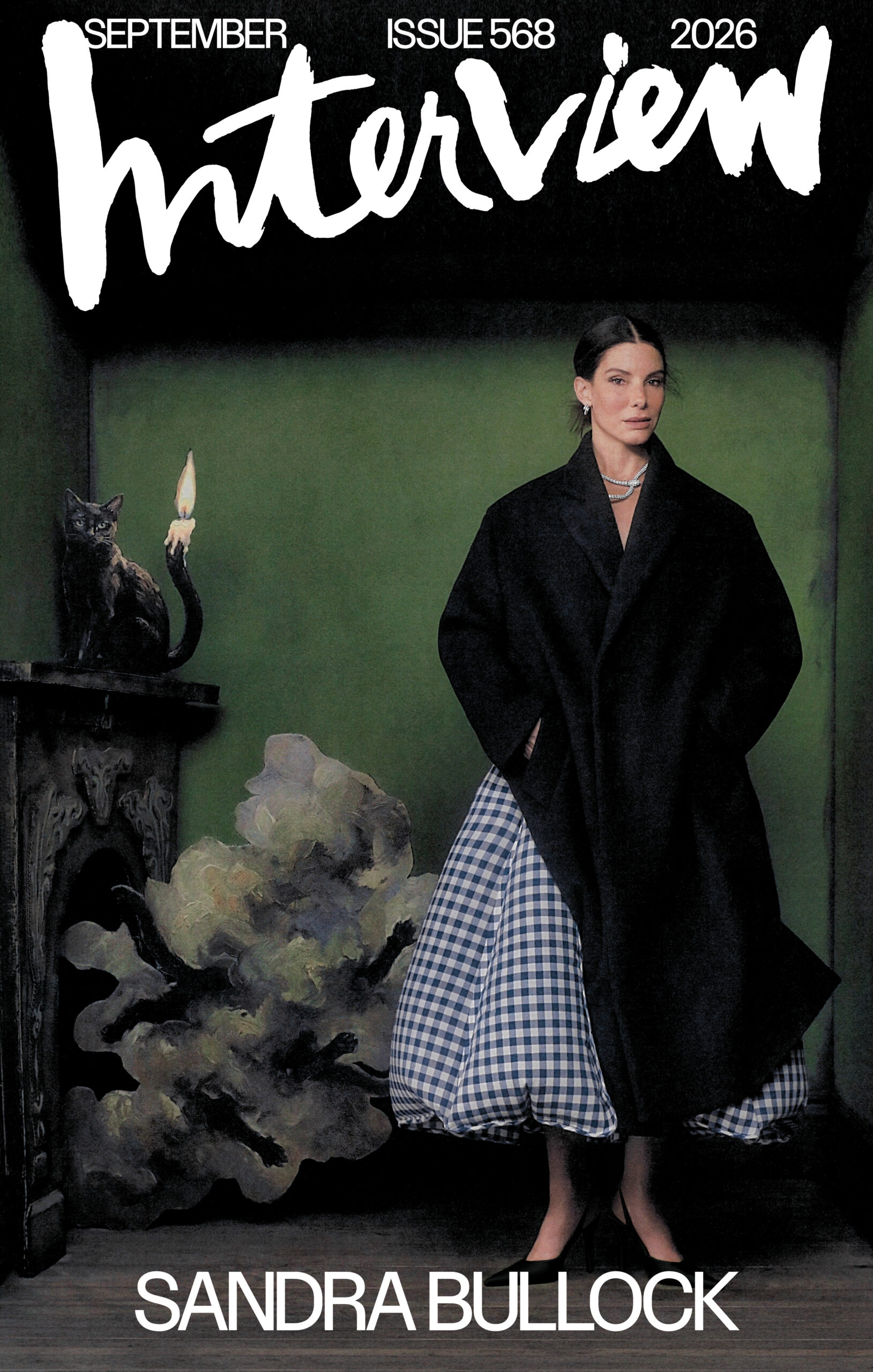Sandra Bullock stands in a green room staring at the camera next to a fireplace and a black cat standing on the mantle.