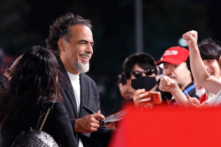 Iñárritu smiles while signing autographs for fans at night